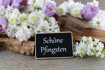 Tafel mit der Aufschrift "Schöne Pfingsten" umrandet von Blumen