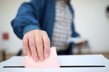 Symbolbild Wahlen; Wahlunterlagen werden in Wahlurne geworfen
